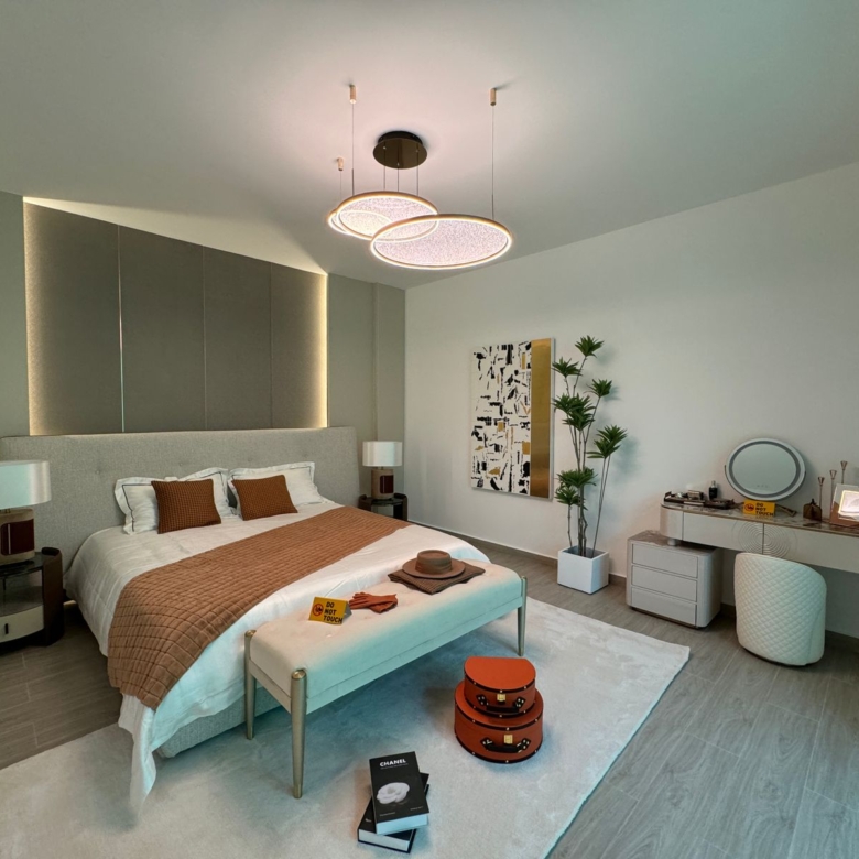 Royal Legend Residence spacious master bedroom featuring an upholstered double bed, modern dressing table, bedside lamps, decorative chandelier, and elegant furnishings.