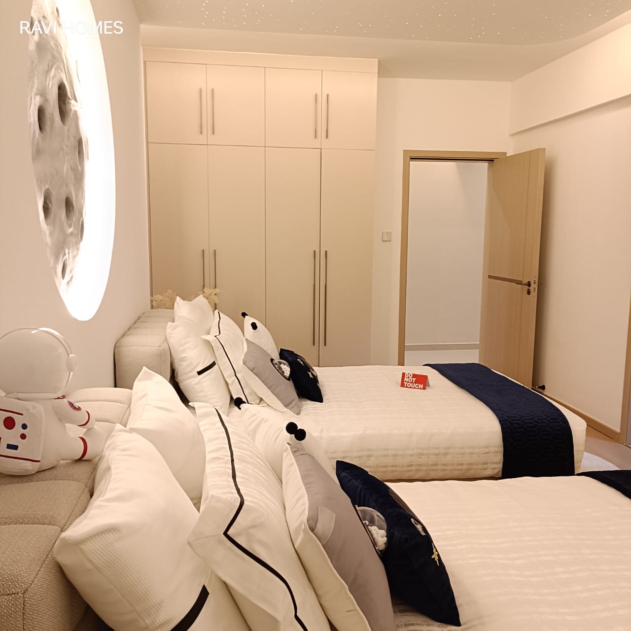 Royal Legend Residence twin bedroom featuring two single beds, fitted wardrobes, white bedding, navy-blue accents, and modern decorative lighting.
