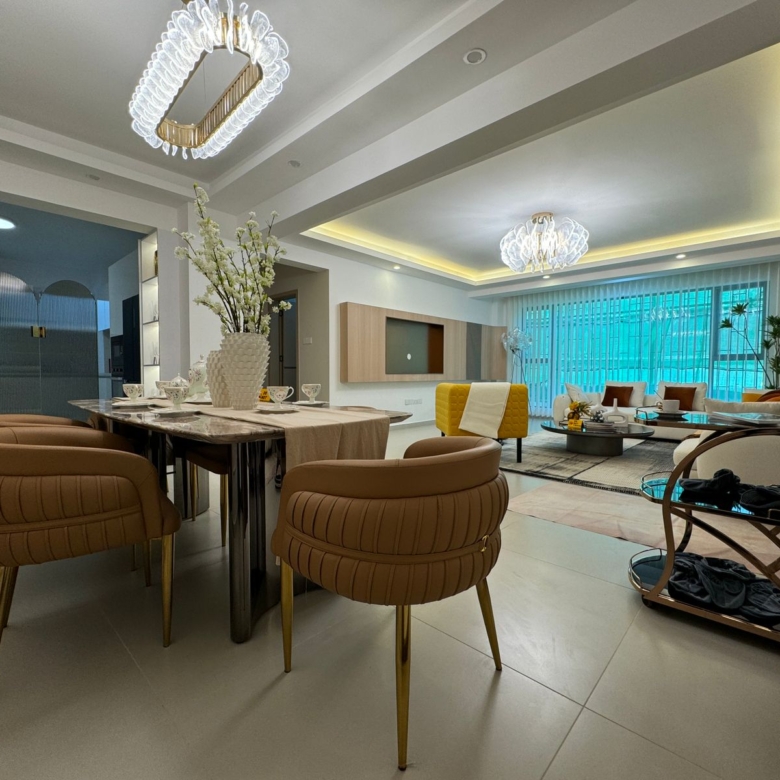 Royal Legend Residence open-plan dining and living area featuring a marble-top dining table, upholstered chairs, decorative chandeliers, and modern lounge furniture.