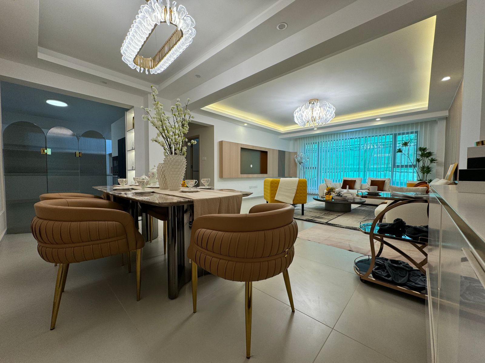 Royal Legend Residence open-plan dining and living area featuring a marble-top dining table, upholstered chairs, decorative chandeliers, and modern lounge furniture.