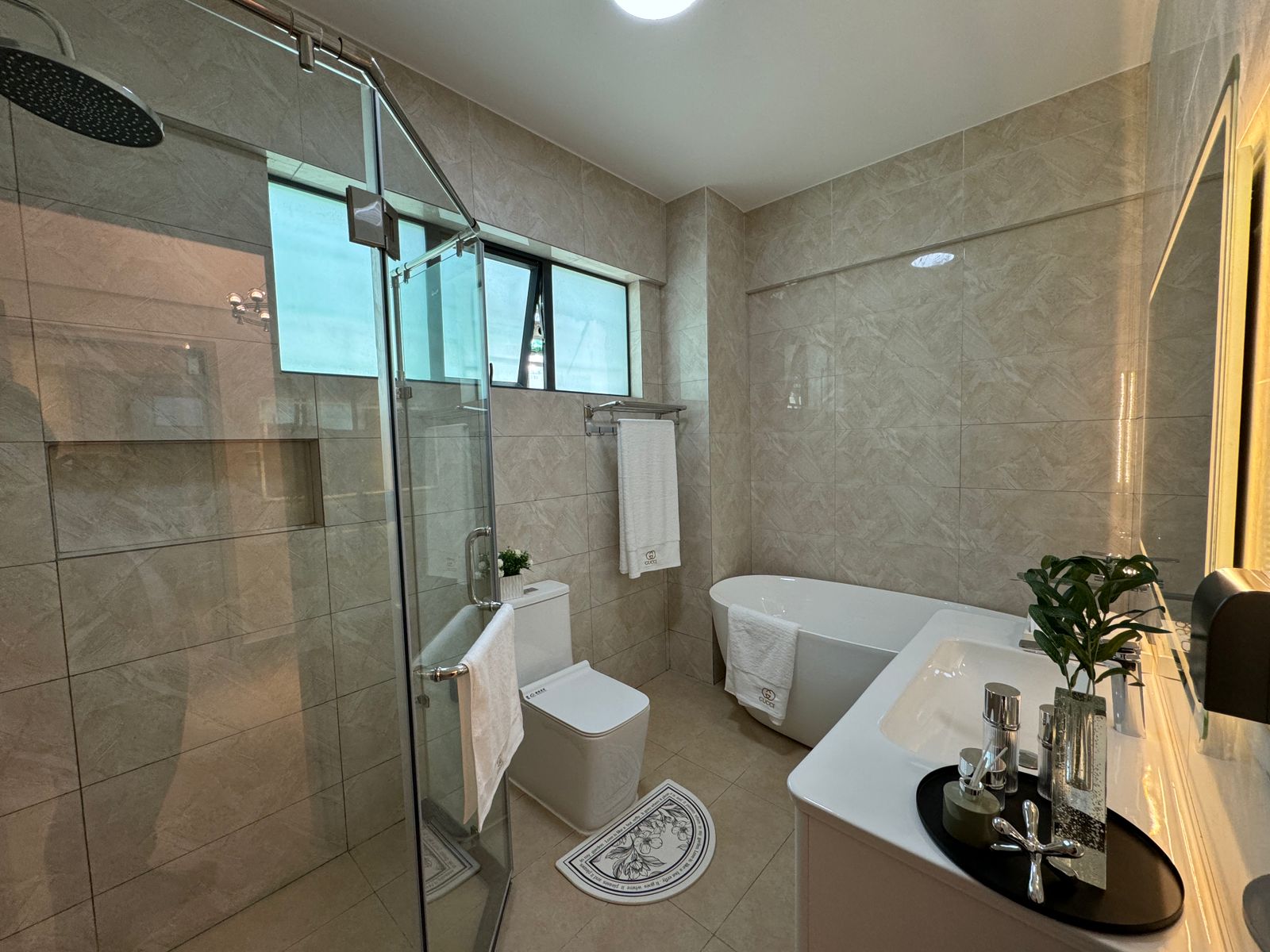 Royal Legend Residence bathroom featuring a glass-enclosed rainfall shower, freestanding bathtub, white vanity, modern toilet, and marble-look tiles.