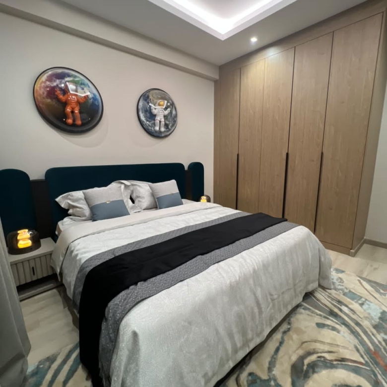 Furnished bedroom at Verona Apartments Westlands with a teal headboard and built-in wardrobes