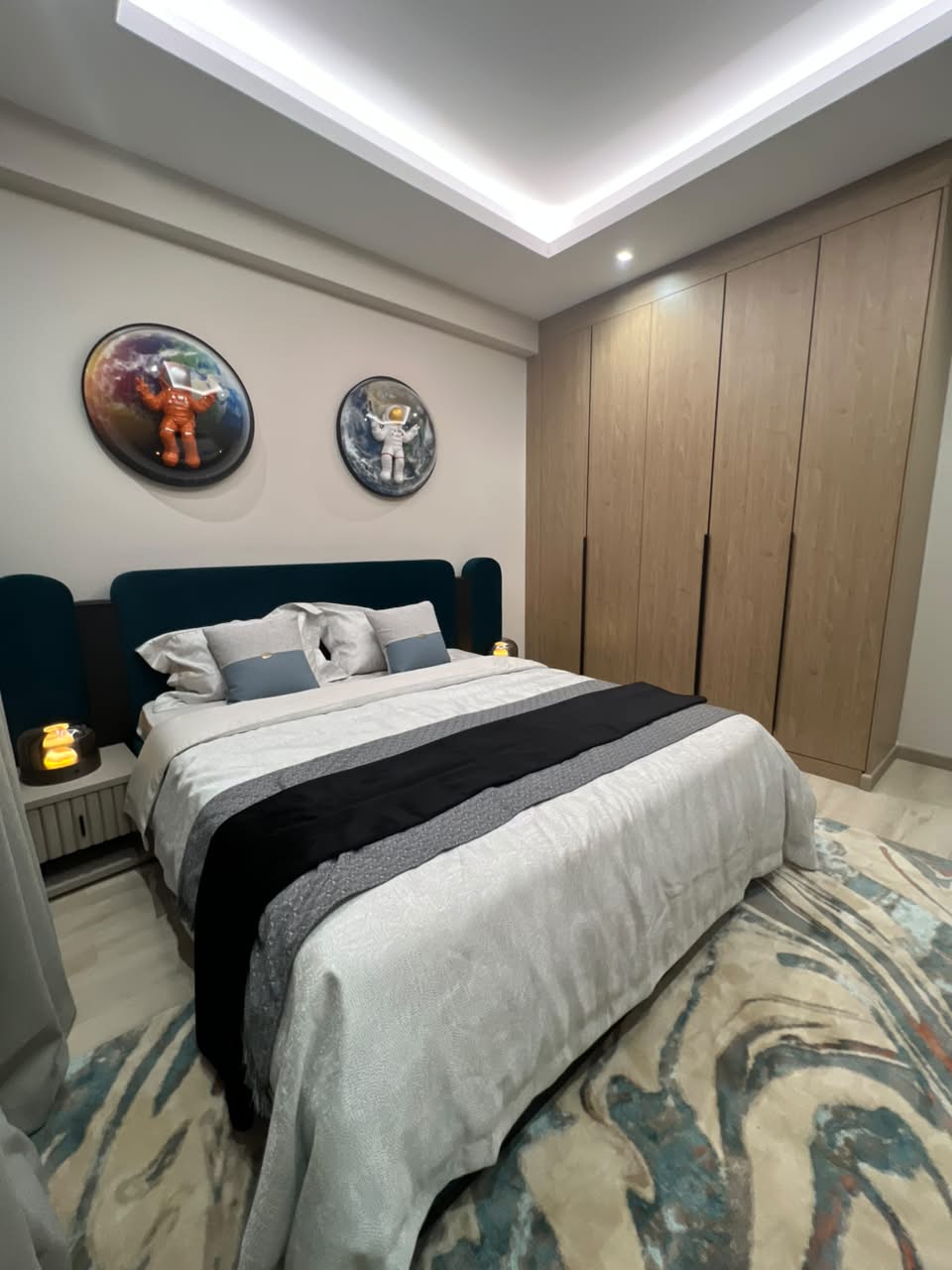 Furnished bedroom at Verona Apartments Westlands with a teal headboard and built-in wardrobes