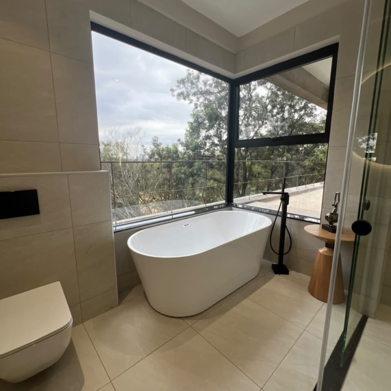 Master bathroom at Verona Apartments Westlands with a freestanding bathtub and corner windows