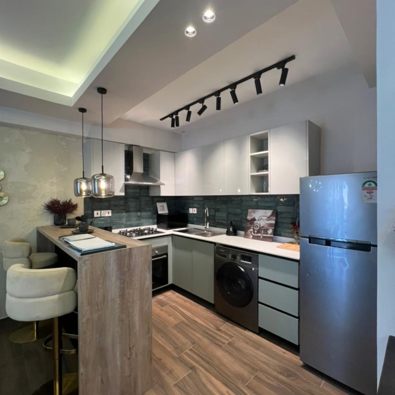 Symphony Residence fitted kitchen featuring a breakfast counter, modern cabinets, gas cooker, built-in oven, refrigerator and washing machine.