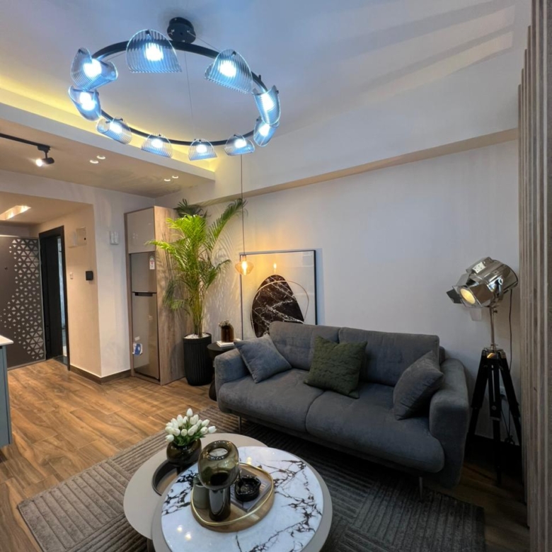 Symphony Residence contemporary lounge featuring a grey sofa, marble-effect coffee table, decorative ceiling light and modern interior furnishings.