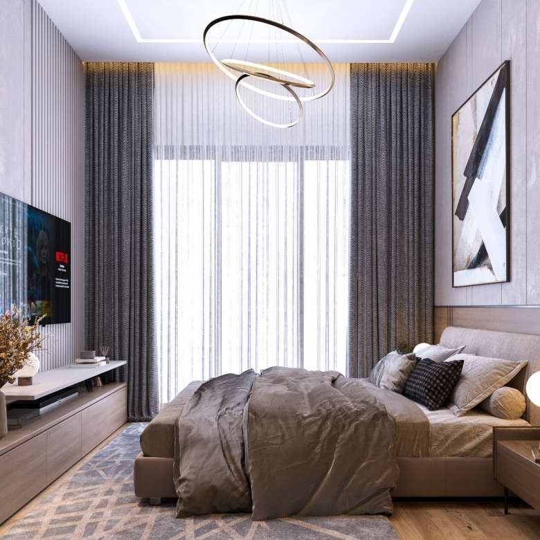 Fountain Residency modern bedroom featuring an upholstered bed, wall-mounted television, elegant ring chandelier, bedside lighting, and floor-to-ceiling curtains.