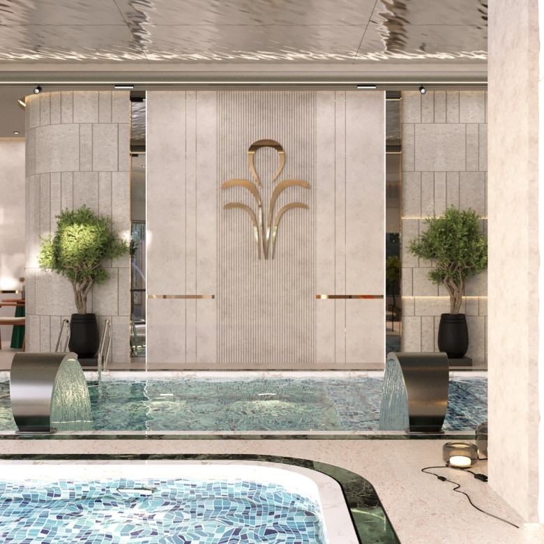 Fountain Residency indoor swimming pool featuring decorative fountain waterfalls, blue mosaic tiles, elegant wall detailing, landscaped plants, and contemporary architectural lighting.