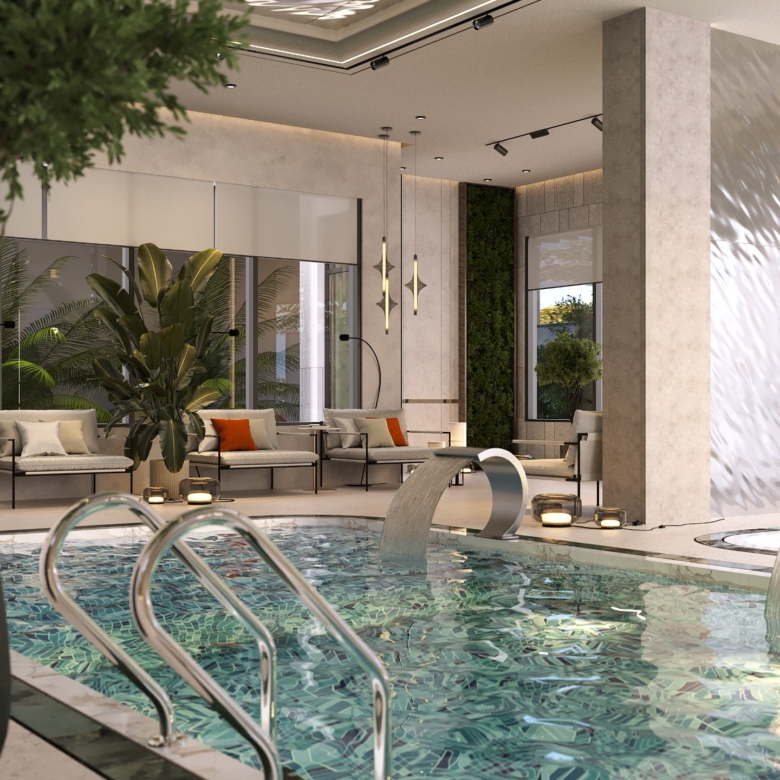Fountain Residency indoor swimming pool featuring mosaic tiles, stainless steel pool ladder, decorative waterfall feature, modern lounge seating, and tropical plants.