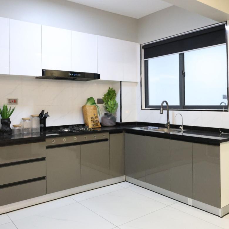 Modern fitted kitchen with white cabinets, black countertops, built-in cooker, sink, and large window
