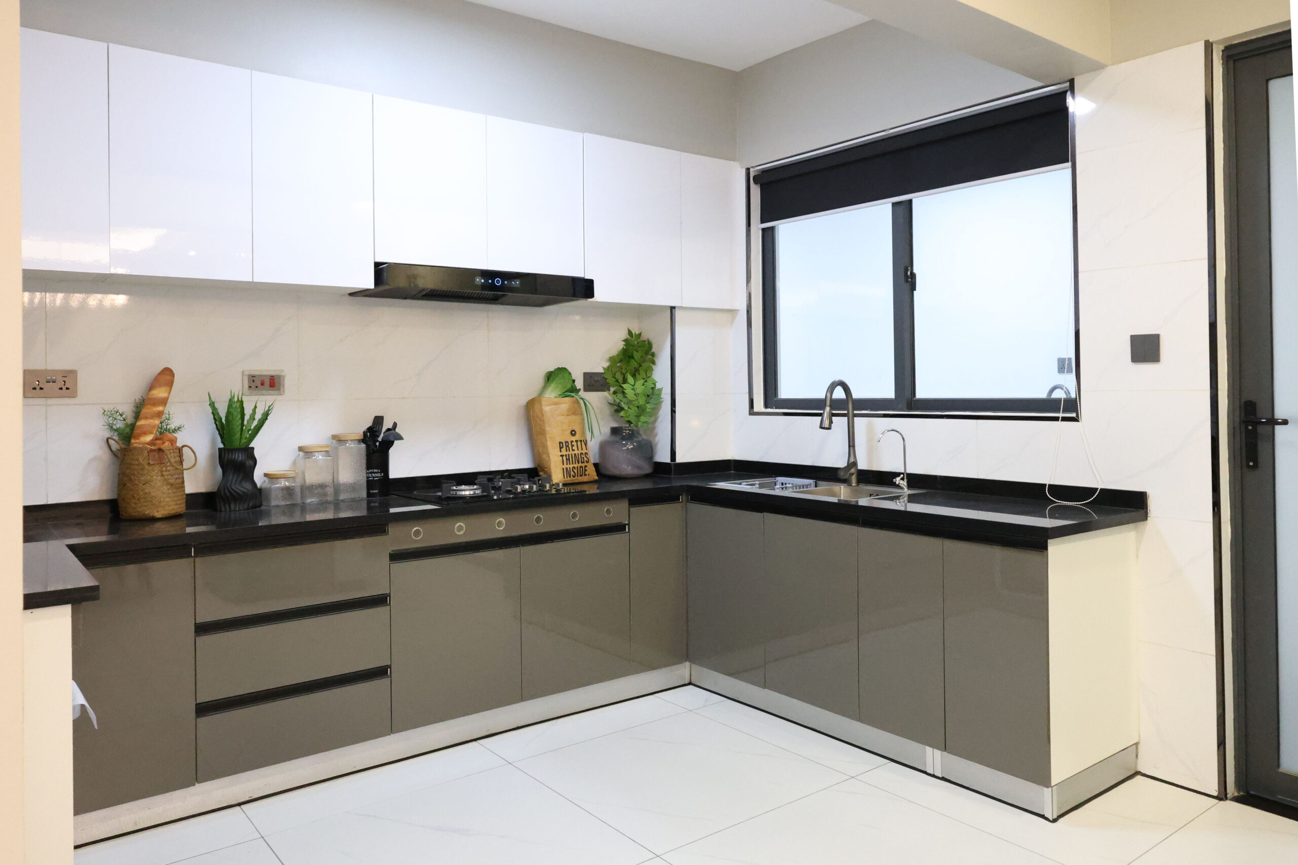 Modern fitted kitchen with white cabinets, black countertops, built-in cooker, sink, and large window