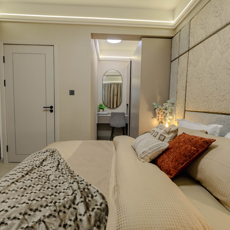 Montbleu apartments 1-bedroom interior in Westlands featuring a comfortable bed, upholstered decorative wall panels, warm LED ceiling lighting, and a dressing table with mirror.
