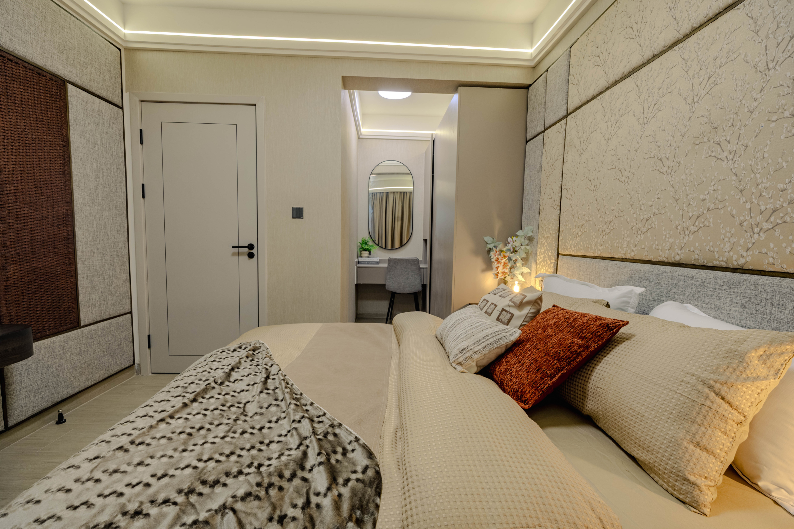 Montbleu apartments 1-bedroom interior in Westlands featuring a comfortable bed, upholstered decorative wall panels, warm LED ceiling lighting, and a dressing table with mirror.