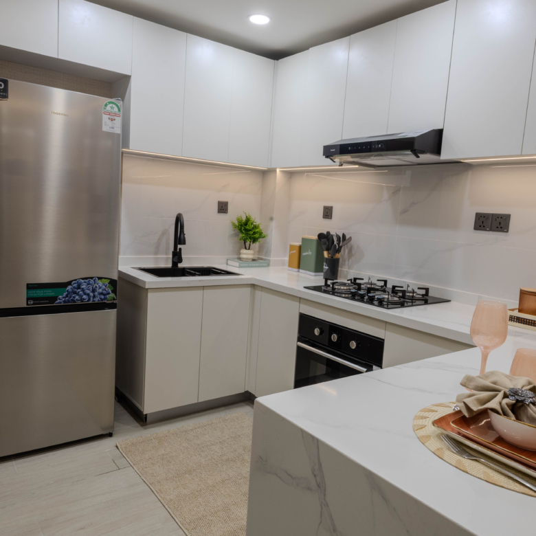 Montbleu apartments 1-bedroom modern kitchen featuring white fitted cabinets, stainless steel refrigerator, black sink, gas hob, extractor hood, and stylish breakfast counter.