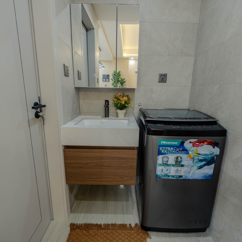 Montbleu apartment laundry area featuring a front-loading washing machine, tiled flooring, large windows, bright natural lighting, and a dedicated utility space.