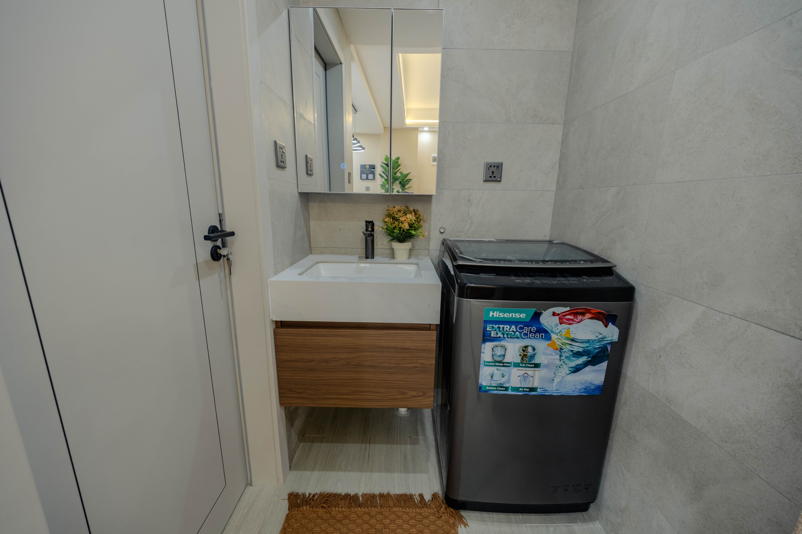 Montbleu apartment laundry area featuring a front-loading washing machine, tiled flooring, large windows, bright natural lighting, and a dedicated utility space.