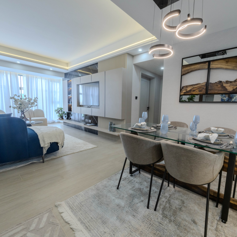 Montbleu apartments 2-bedroom kitchen featuring modern white cabinets, marble-effect breakfast counter, rust-coloured bar stools, pendant lights, stainless steel refrigerator, and fitted appliances.