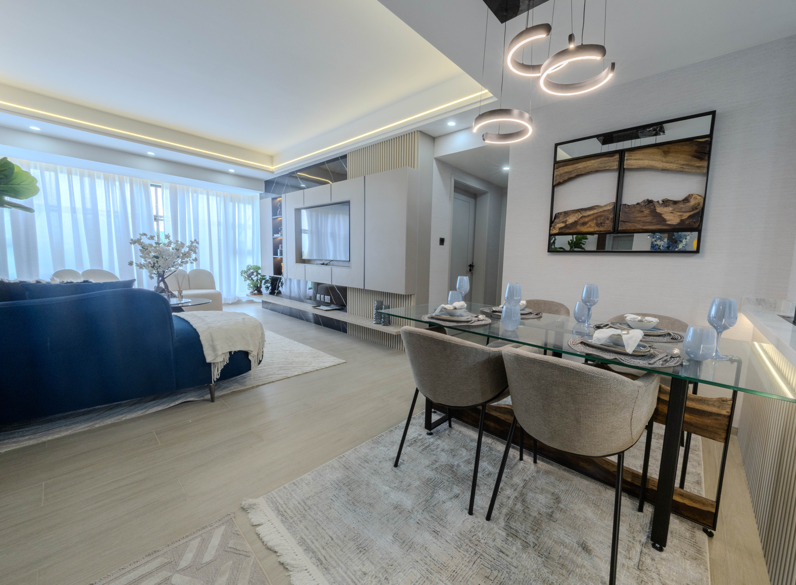 Montbleu apartments 2-bedroom kitchen featuring modern white cabinets, marble-effect breakfast counter, rust-coloured bar stools, pendant lights, stainless steel refrigerator, and fitted appliances.