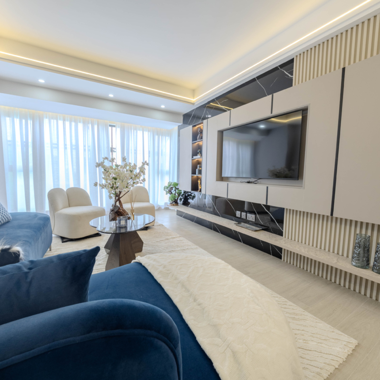 Montbleu apartments 2-bedroom open-plan living and dining area featuring a blue upholstered sofa, glass dining table, modern pendant lights, entertainment wall, and large windows.