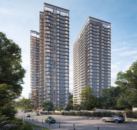 Modern twin high-rise apartment buildings with glass balconies, landscaped grounds, and a city road