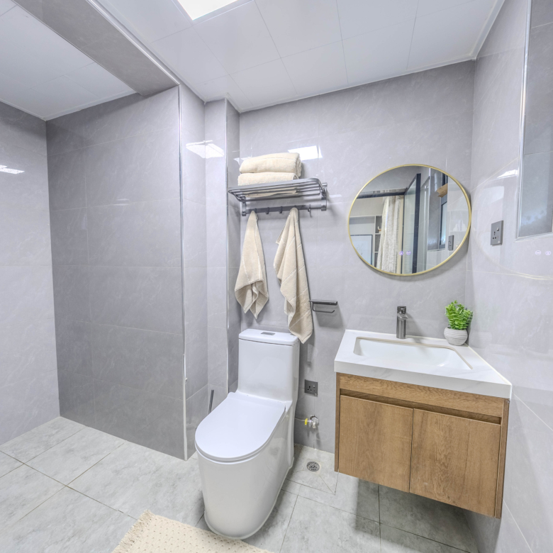 Marina Bay Phase III bathroom interior with rainfall shower, modern toilet, floating wooden vanity, and circular mirror.