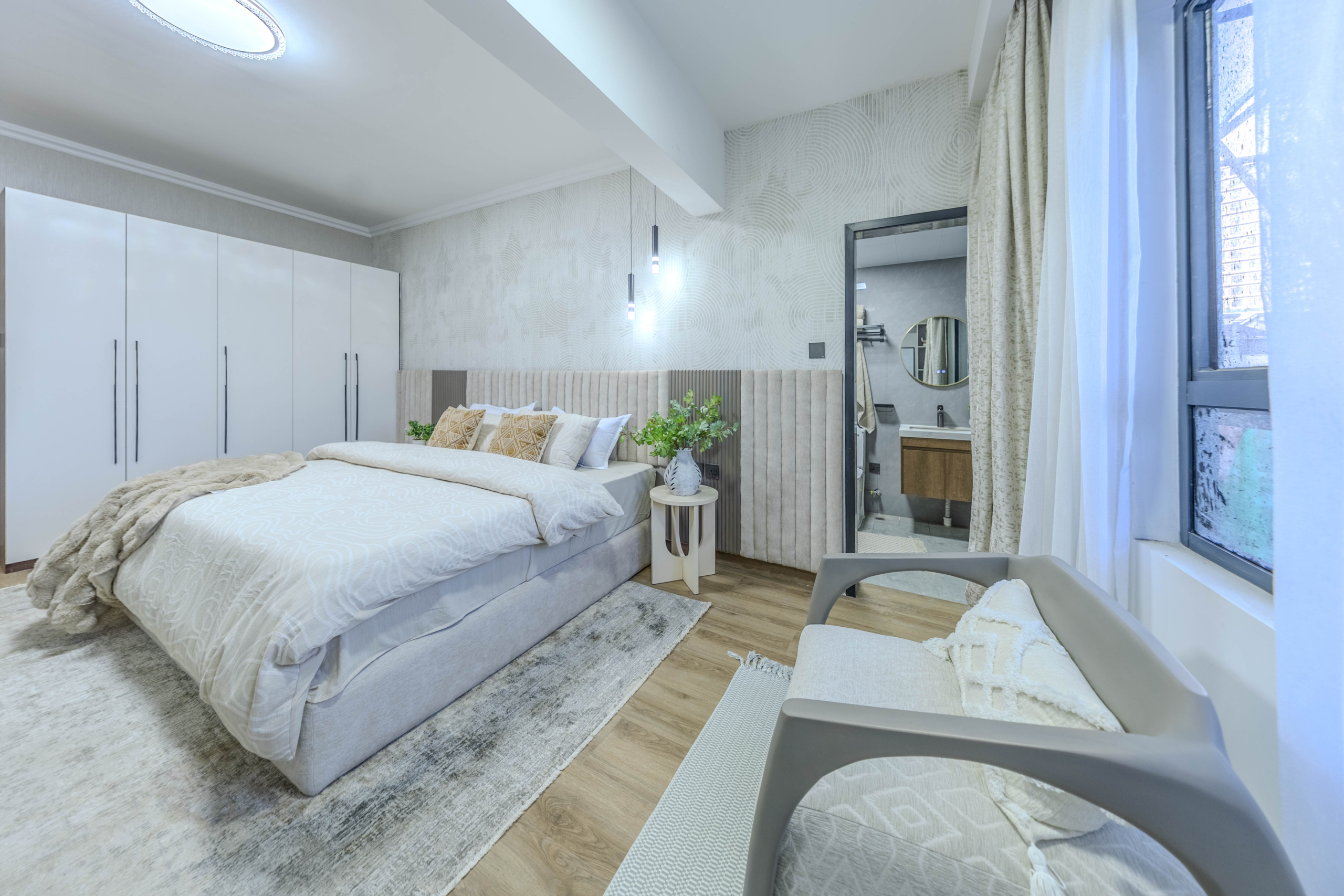 Marina Bay Phase III bedroom with fitted white wardrobes, upholstered bed, contemporary pendant lighting, and ensuite bathroom access.