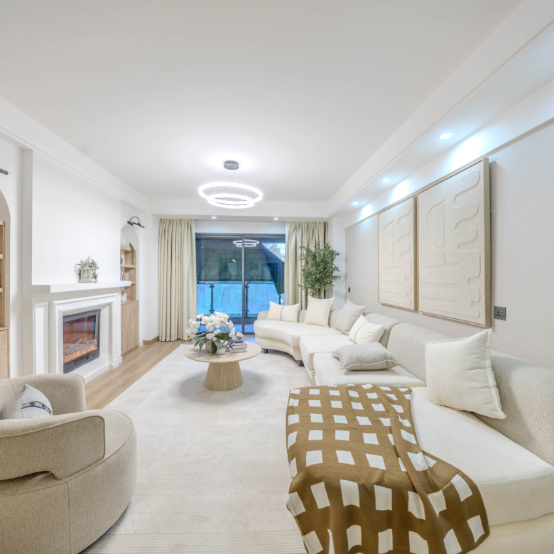 Marina Bay Phase III spacious living room featuring a cream sectional sofa, decorative fireplace, modern ceiling lights, and balcony access.