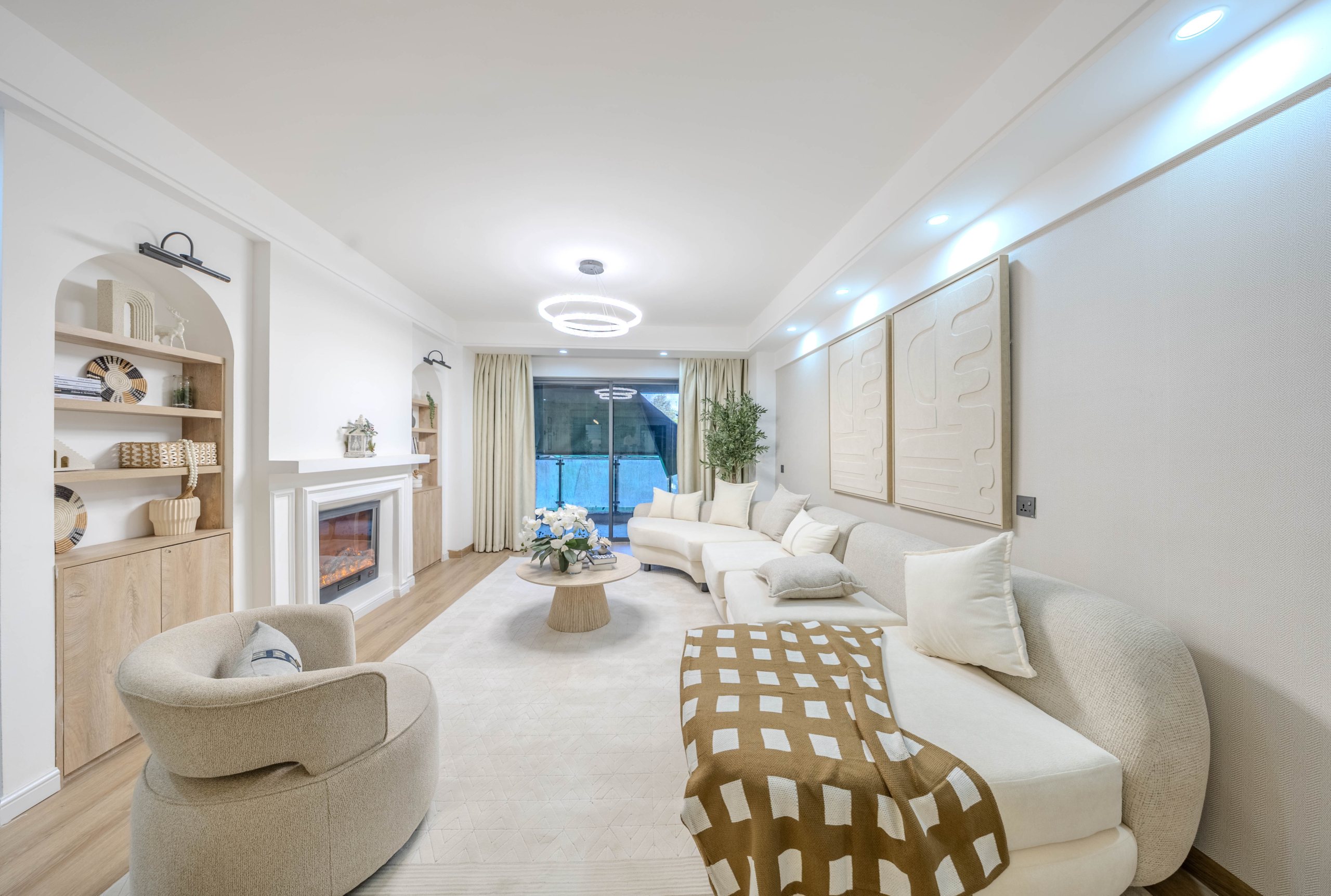 Marina Bay Phase III spacious living room featuring a cream sectional sofa, decorative fireplace, modern ceiling lights, and balcony access.