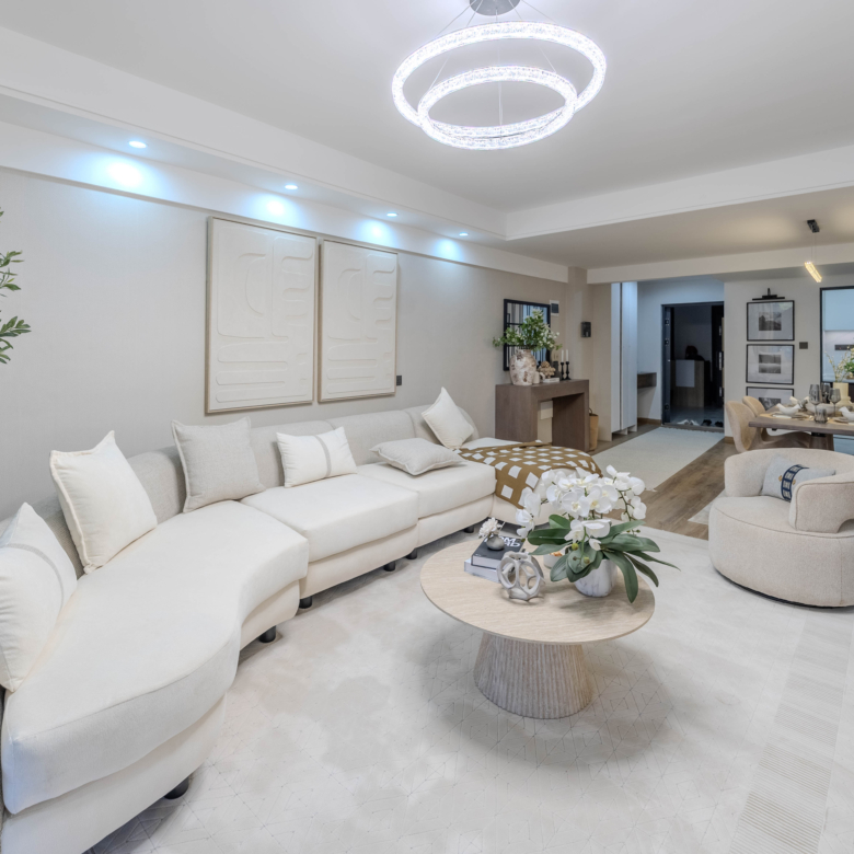 Marina Bay Phase III open-plan living room with large sectional sofa, modern coffee table, pendant lighting, and adjoining dining area.