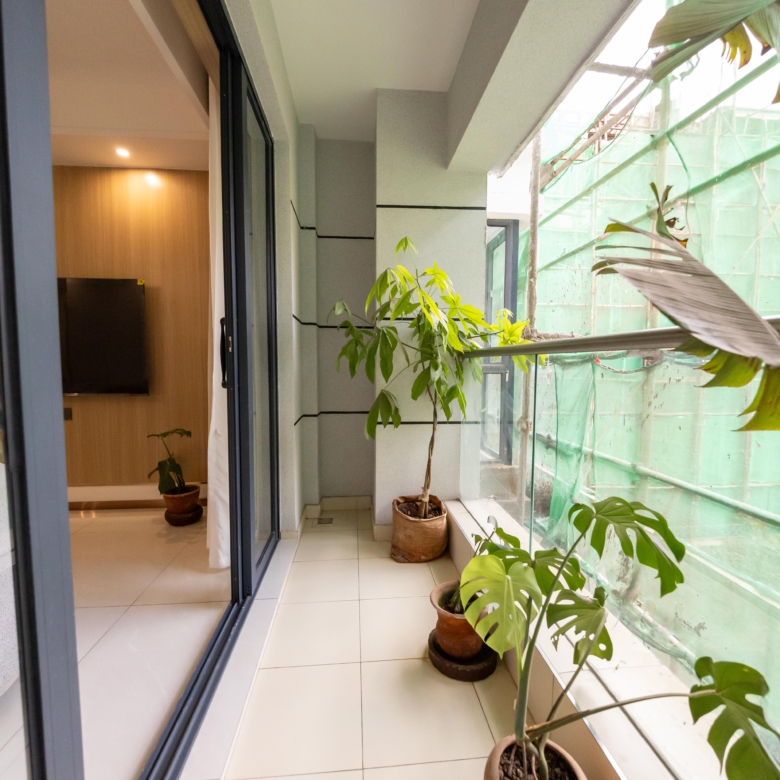 Rhapta One Residency private apartment balcony with tiled flooring, glass railings, potted plants, and sliding glass doors.