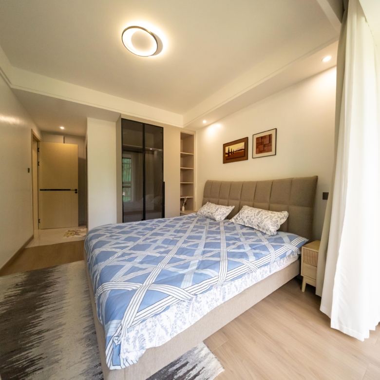 Rhapta One Residency spacious bedroom with double bed, blue patterned bedding, fitted wardrobes, bedside cabinet, and wooden flooring.