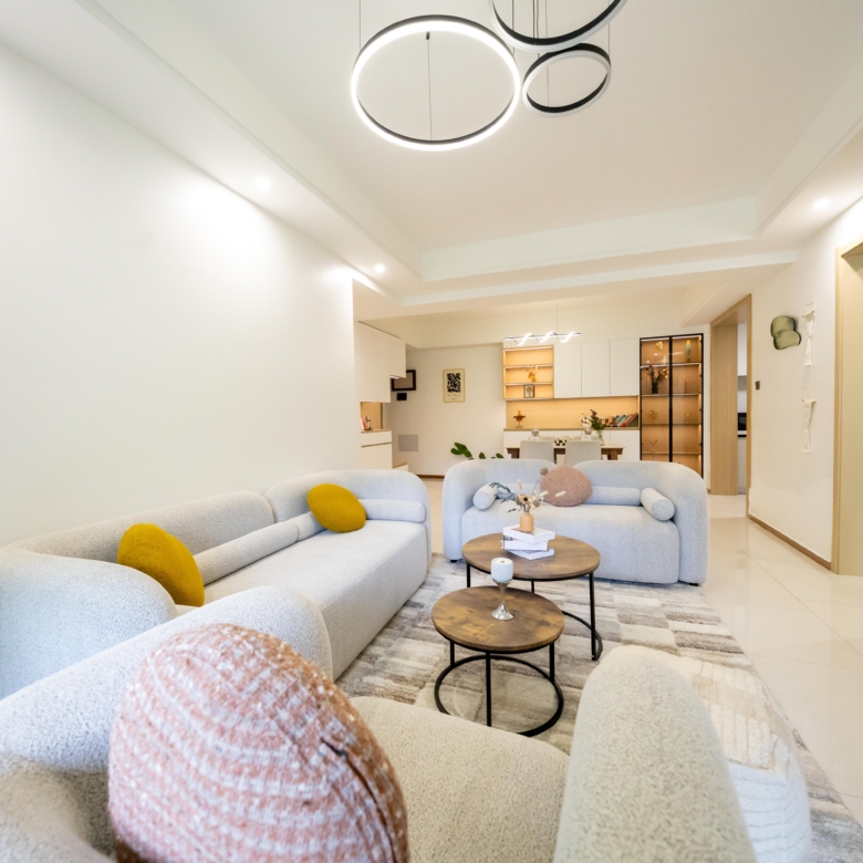 Rhapta One Residency contemporary lounge with cream upholstered sofas, circular coffee tables, modern chandelier, and open-plan dining space.