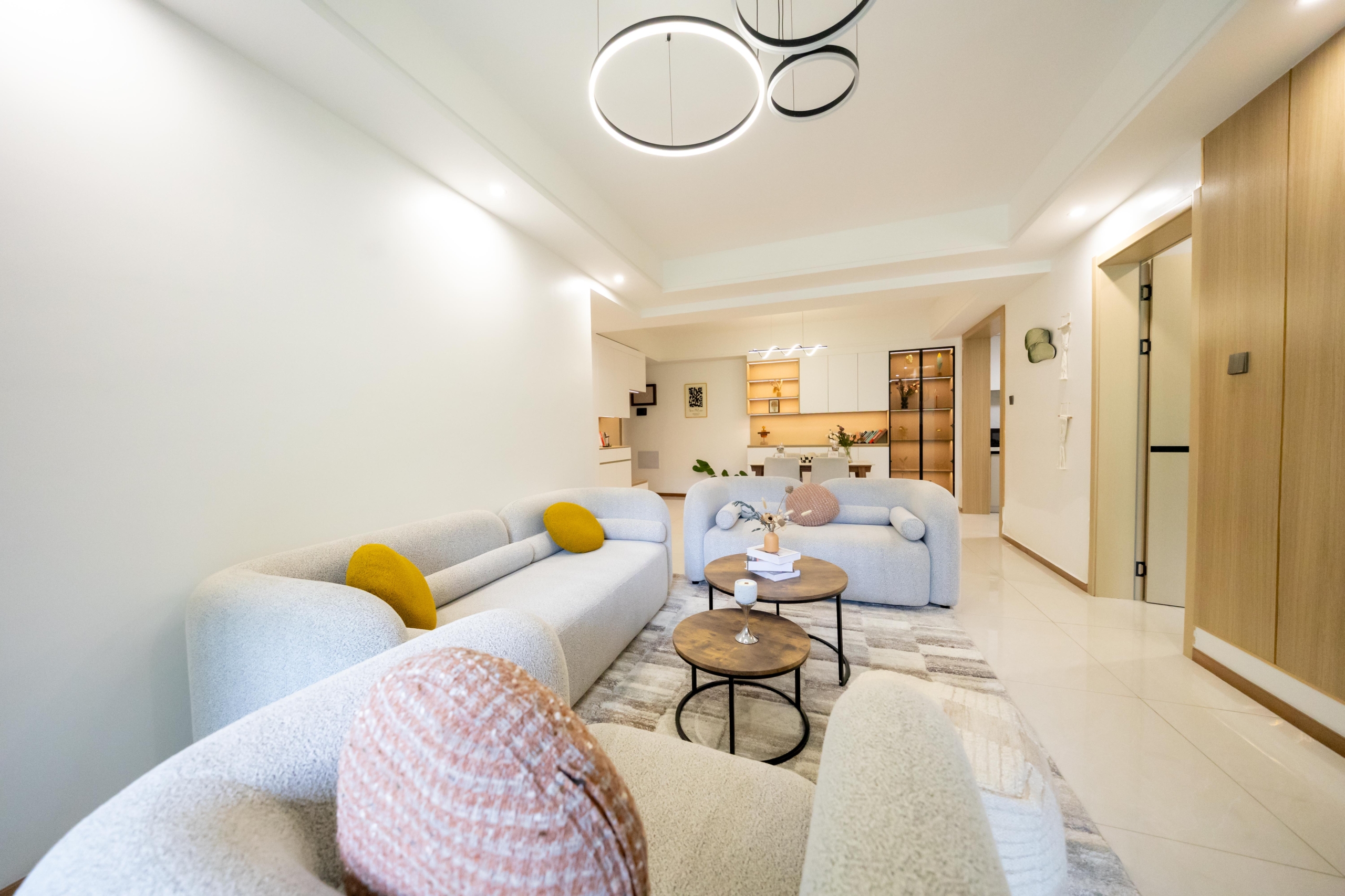 Rhapta One Residency contemporary lounge with cream upholstered sofas, circular coffee tables, modern chandelier, and open-plan dining space.