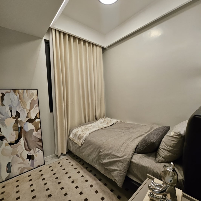 Compact furnished bedroom with neutral décor and full-length curtains at ILU Green Homes