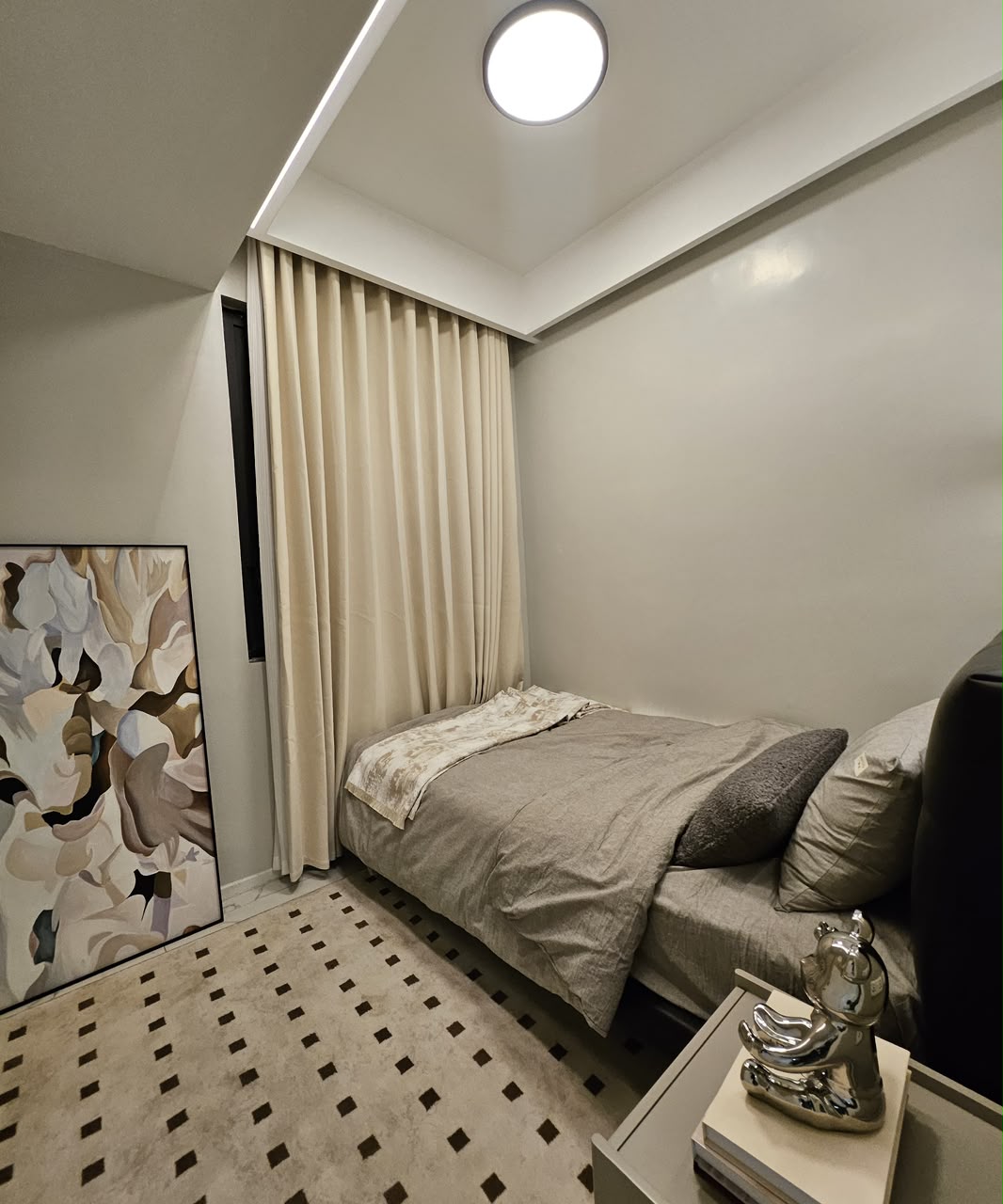 Compact furnished bedroom with neutral décor and full-length curtains at ILU Green Homes