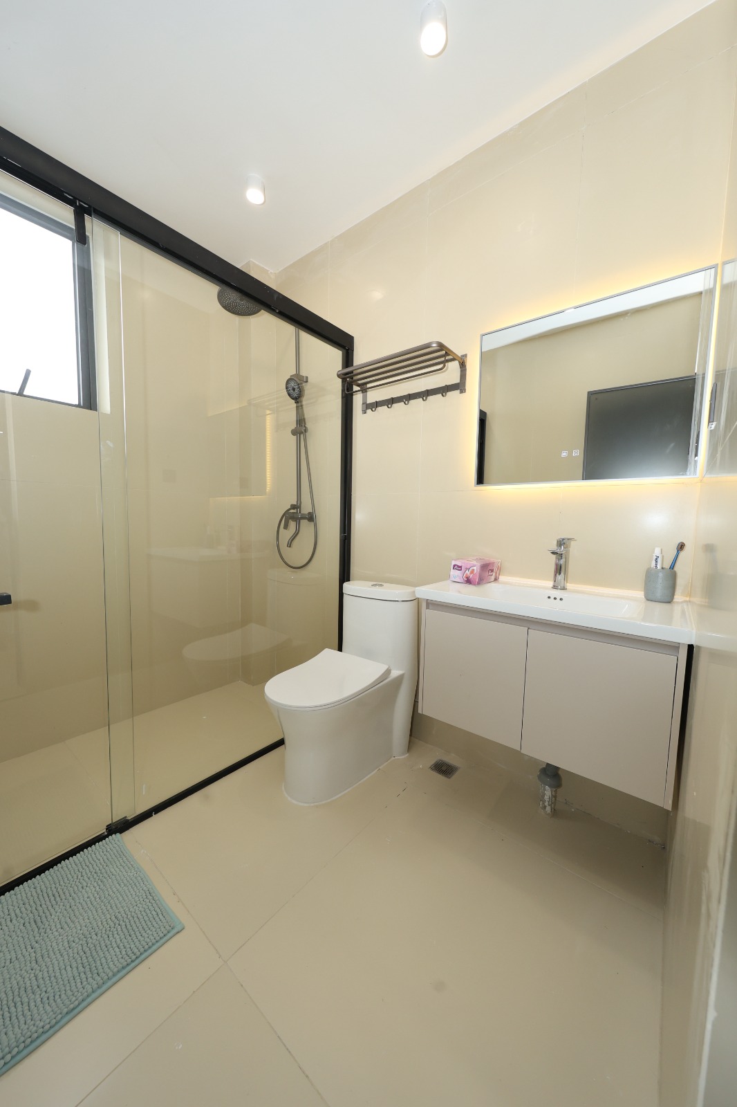 Bright apartment bathroom with vanity and glass shower at Luster Arbor Residency