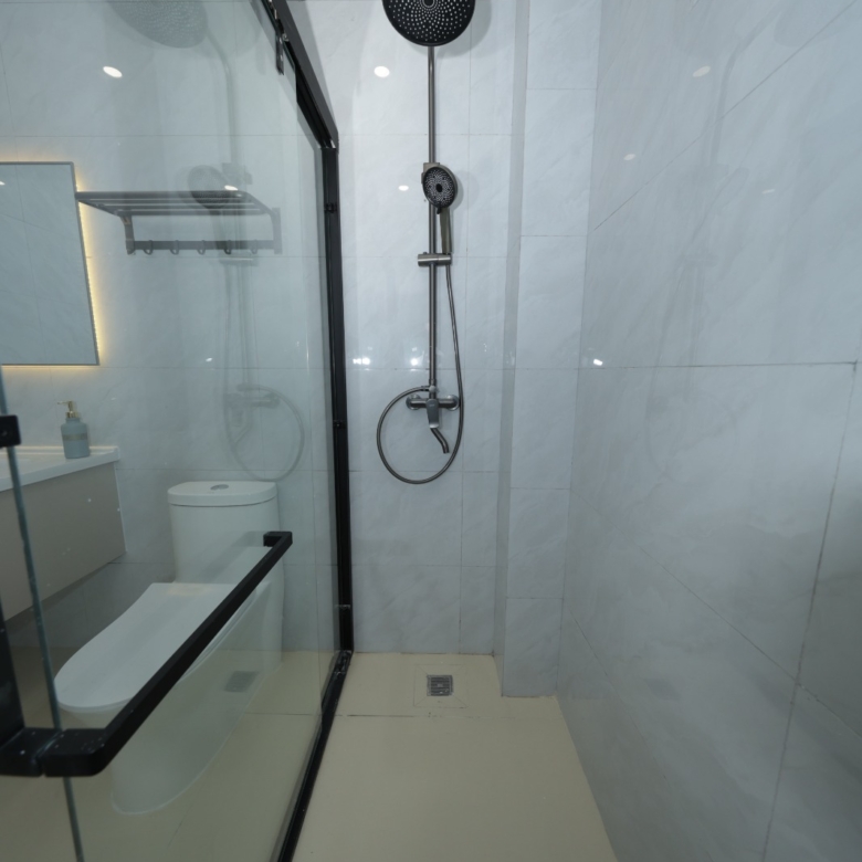 Bathroom with glass shower enclosure and rainfall shower at Luster Arbor Residency