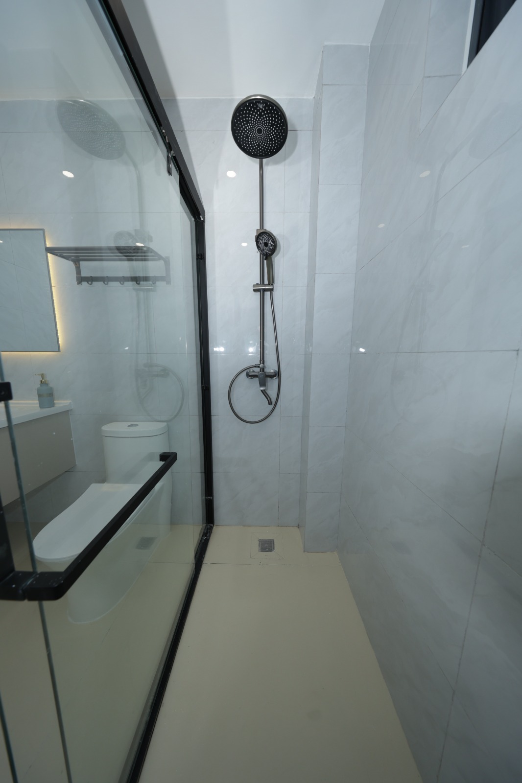 Bathroom with glass shower enclosure and rainfall shower at Luster Arbor Residency