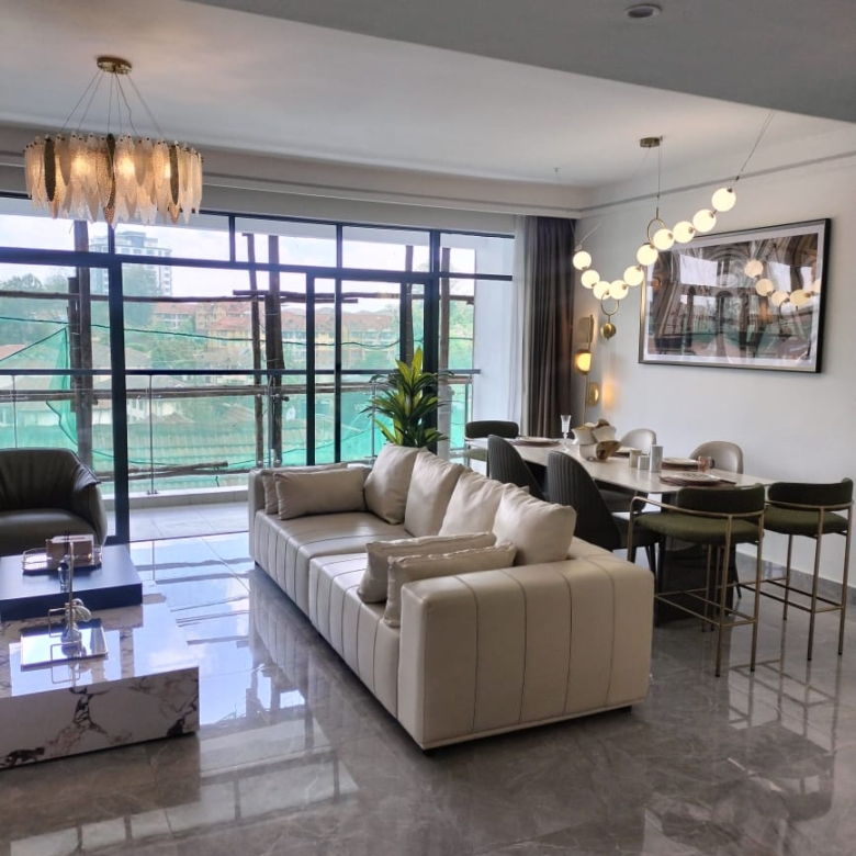 Riara One Residency furnished living and dining room featuring cream sofa, modern dining table, chandelier, marble-look flooring, and balcony.