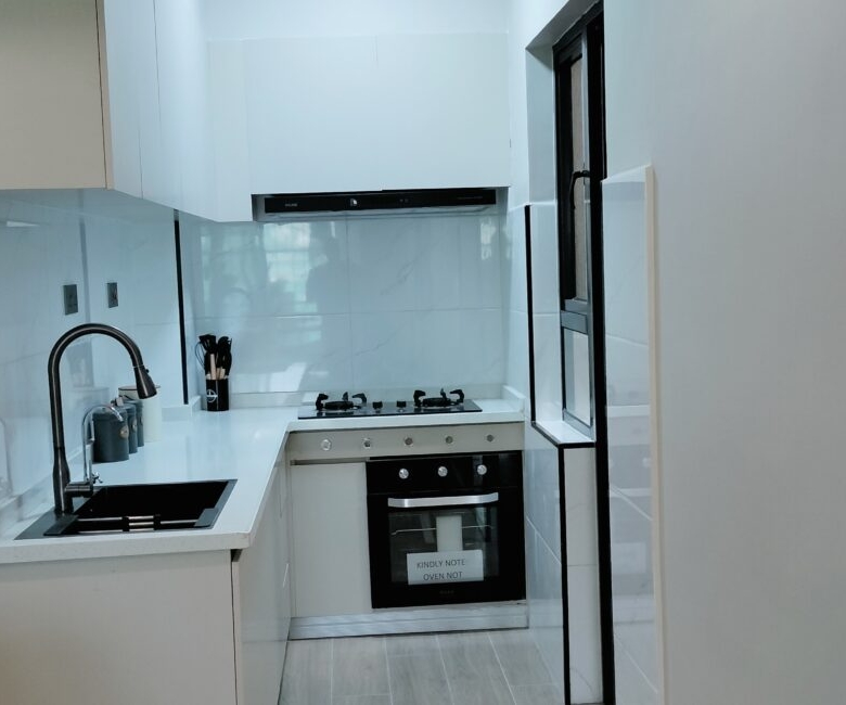Citi Rise Residency in Westlands modern fitted kitchen with white cabinets, black sink, oven and cooktop
