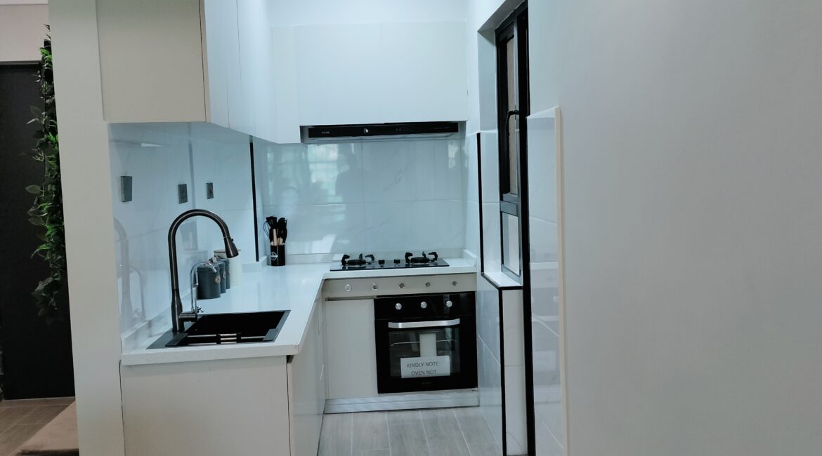 Citi Rise Residency in Westlands modern fitted kitchen with white cabinets, black sink, oven and cooktop