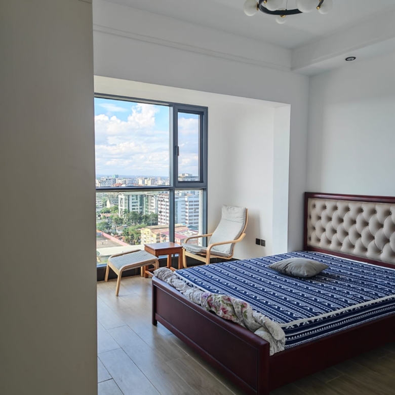 Spacious master bedroom with large windows and polished wood-effect flooring in Kilimani.