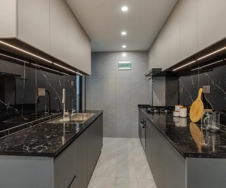 Fitted apartment kitchen with black stone countertops at Oak West Residency