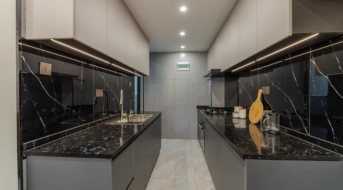 Fitted apartment kitchen with black stone countertops at Oak West Residency