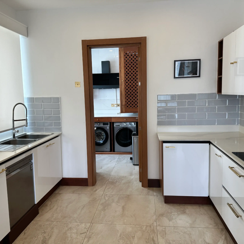 White fitted kitchen with double sink and utility-room access