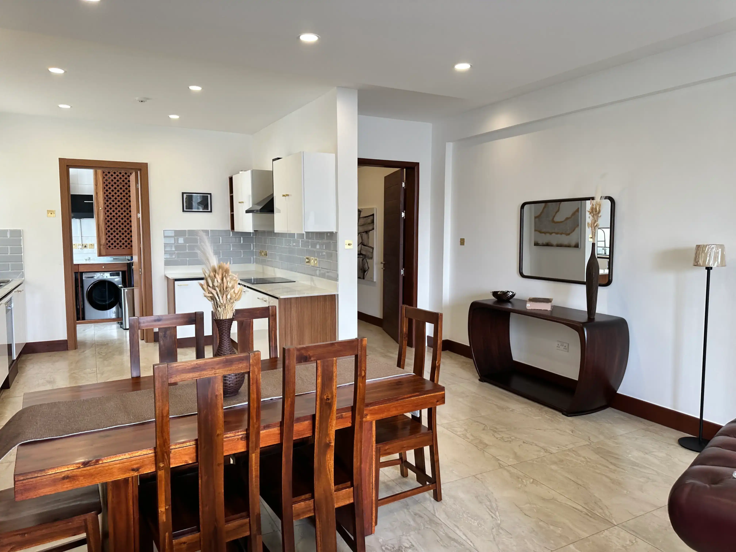 Six-seat wooden dining table beside a fitted kitchen