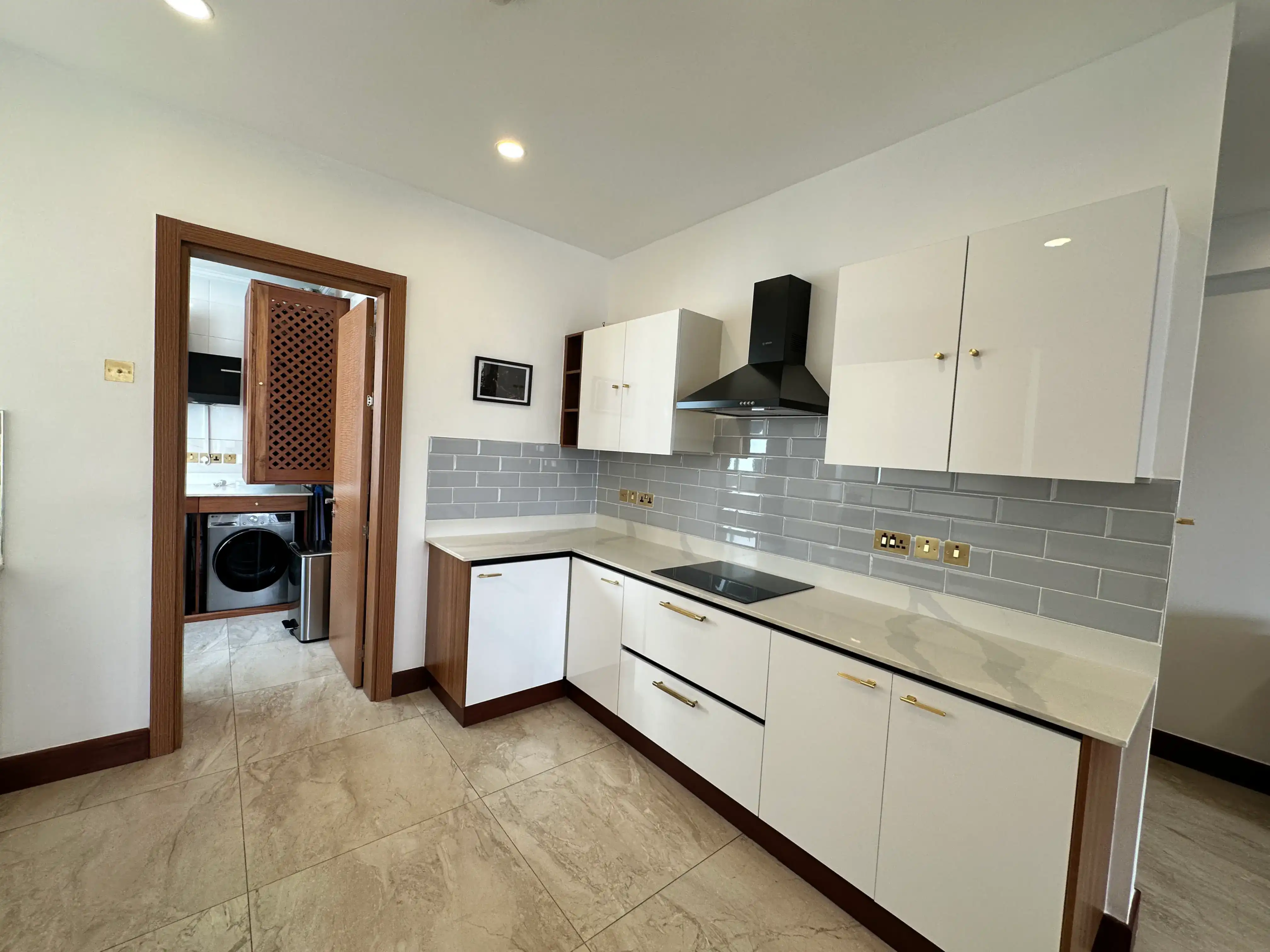 Modern white kitchen cabinets with stone worktop and electric hob