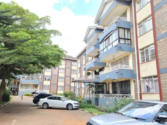 Exterior view of a four bedroom apartment complex with balconies, landscaped grounds and parking in Riverside Drive