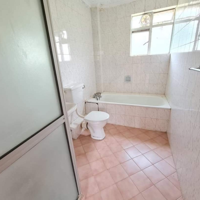 Bathroom with bathtub, tiled walls and frosted glass shower screen in a Riverside Drive apartment