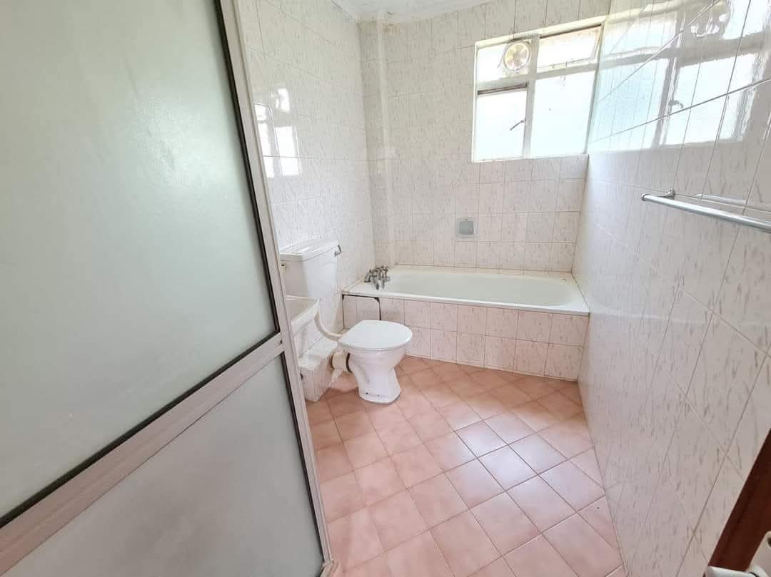Bathroom with bathtub, tiled walls and frosted glass shower screen in a Riverside Drive apartment